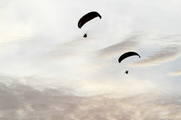 Two distant figures on powered paragliders soaring in the sky