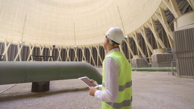 Engineer in white helmet is working.
The engineer working at the power generation plant works with his tablet.
