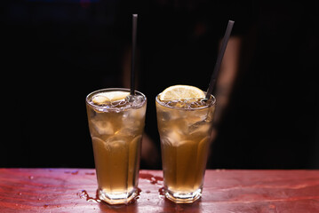 Two cocktails with lemon on the bar. The bartender prepares drinks for guests. Night life, club life. Great serving of cocktails. Amazing cocktails
