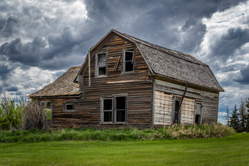 Fototapeta na wymiar Stormy skies over a stately old, abandoned home on the prairies of Saskatchewan 