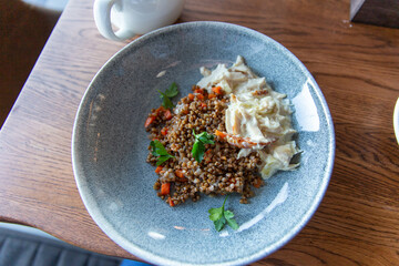 Delicious buckwheat porridge with sauce and parsley in a blue plate