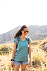 Naklejka premium young girl with a backpack walks along a mountain path