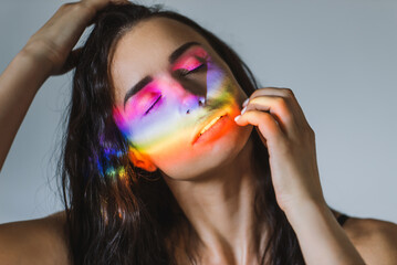 Closeup portrait of smiling woman with ray of rainbow light on her face. Rainbow optical flare from...