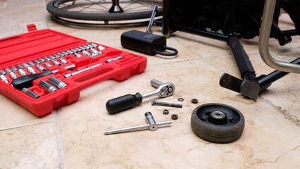 a small wheel from a wheelchair lies on the floor next to a tool kit