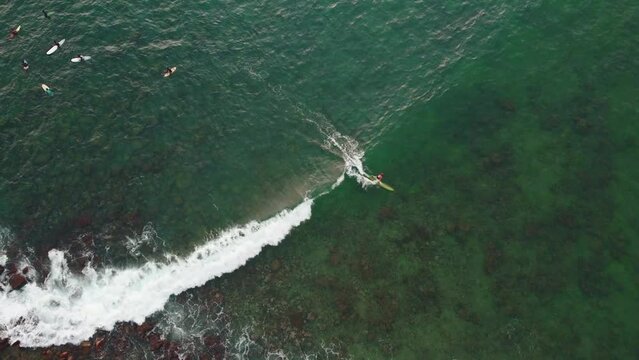 Surferzy w oceanie czekający na fale, aktywny wypoczynek, tropikalny krajobraz, ujęcie z drona.