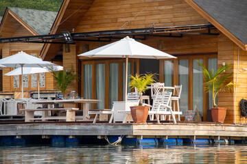 A place to relax on the terrace of the house consisting of wooden chairs and tables with a view of the blue sea
