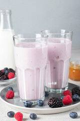 Smoothie from fresh berries, natural yogurt and honey in two tall glasses on gray background, Vertical format