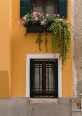 Fototapeta na wymiar yellow facade with windows and flowers in Venice, Italy