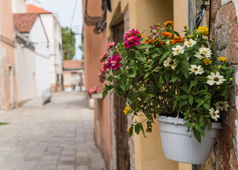 Fototapeta na wymiar white pot with colorful flowers hanging outside a house in Italy