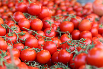 Ripe red cherry tomatoes with green leaves on market