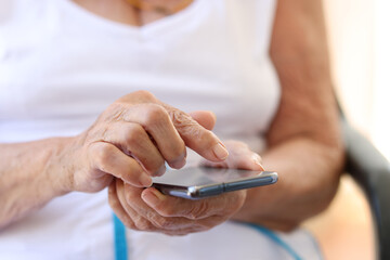 Old grandmother holding modern cellphone in hands. Woman using smartphone