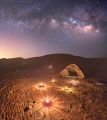 Beautiful Camp wit tent and candles in an empty dark isolated desert under the milkyway and millions of stars in the sky