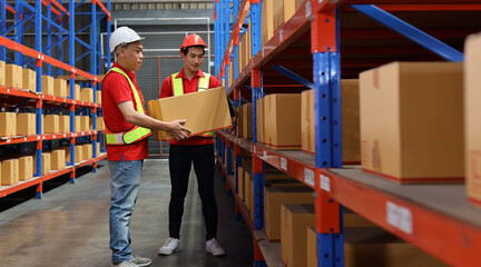 Group of warehouse workers men with hardhats and reflective jackets carrying a large box for...
