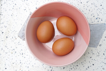 Three fresh eggs in a bowl are cooking.