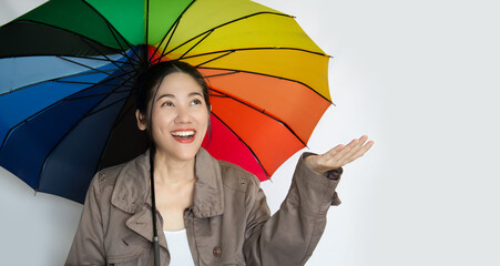 Asian beautiful  woman holding colorful umbrella looking up to see raining with smile and a happiness