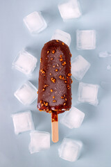 popsicle in chocolate and ice cubes on a blue background, selective focus