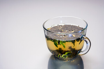 a transparent cup with green tea is reflected in the gray glass, copy space