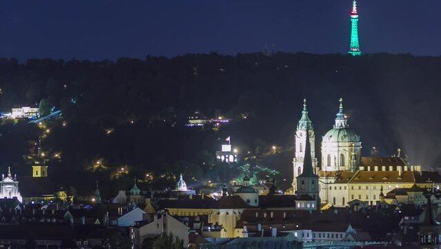 Aerial night top view of the church of saint nicolas with petrin hill behind it timelapse. Traffic on the road