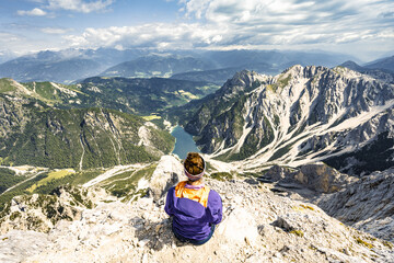 Young woman enjoys beautiful view from Seekofel on Braies Lake in the Dolomite mountains at noon. Seekofel, Dolomites, South Tirol, Italy, Europe.