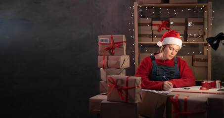 Girl in Santa hat own small business on shopping online at home office packaging on background is a...