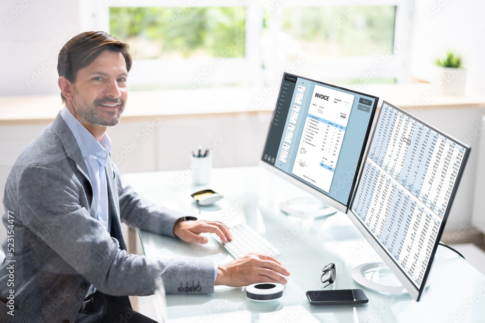 Aufkleber looking at invoice and spreadsheet on computer