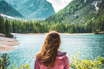 Young woman enjoys beautiful view on Baires Lake in the Dolomite mountains in the afternoon. Braies...