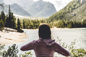 Young woman enjoys beautiful view on Baires Lake in the Dolomite mountains in the afternoon. Braies...