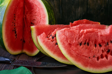 On a dark dish are slices of watermelon, in the background a cut watermelon.Close-up,