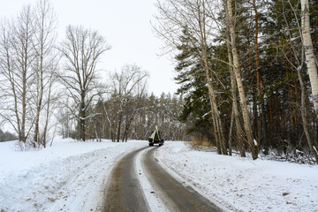The tractor is driving on a snowy road. Snow removal on city streets.