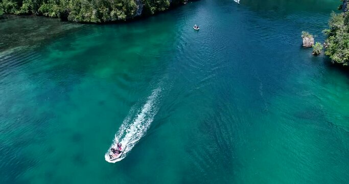 Aerial shot of zodiac boat floating over turquoise water near rocky islands