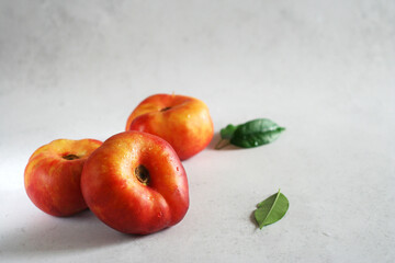 Three peaches lie on a light concrete table. Minimalism