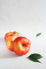 Three juicy fig peaches lie on a gray concrete table. Leaves lie nearby