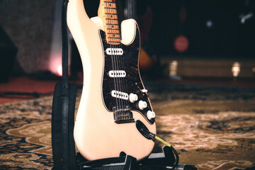 Close-up of a white cream colored electric guitar on a stand on a stage