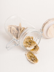 Banana chips in glass jar on white background. Dried bananas. Healthy sweets