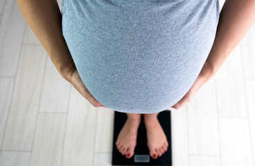 Pregnant woman with barefoot on scales control her weight gain. Healthy pregnancy.