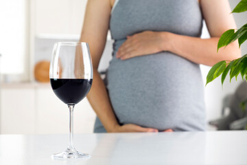 Pregnant woman and glass of wine. Pregnancy and alcohol. Prenatal care and harm of bad habits.