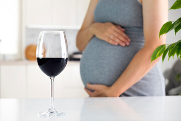 Pregnant woman and glass of wine. Pregnancy and alcohol. Prenatal care and unhealthy lifestyle.