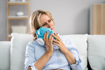 Upset Young Woman Touching Cheek With Cold Water Bag