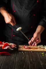 Chef pricks raw meat on a skewer. The process of cooking meat shish kebab in the kitchen by the hands of a cook.