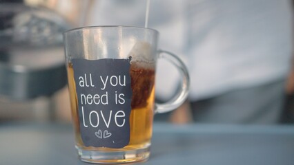 Close up view of woman brews tea in glass cup.