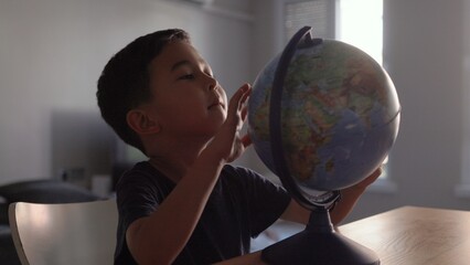 Naklejka premium Cute Preschooler explores countries on the globe