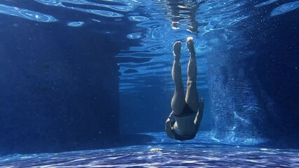 Slow motion video of little girl practice swim and dive underwater in swimming pool at summer vacation