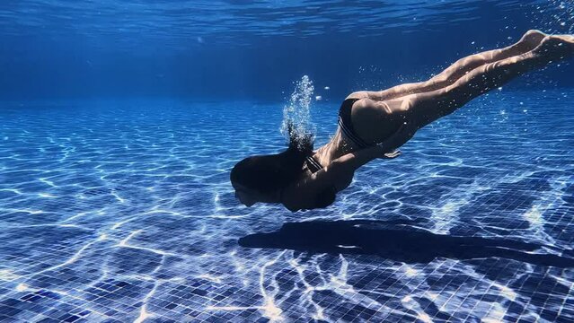 Slow motion video of little girl practice swim and dive underwater in swimming pool at summer vacation