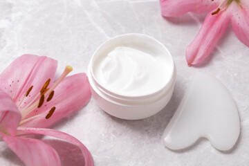 Gua Sha stone for face massage. Container with bodycare and skincare cream. Anti age, lifting and toning treatment