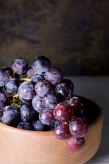 bunch of black grapes on a wooden plate
