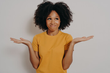 Young african woman standing with clueless and funny confused expression with arms and hands raised
