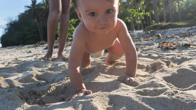 Charming little baby crawling on the sand at the beach in vacation on summer.