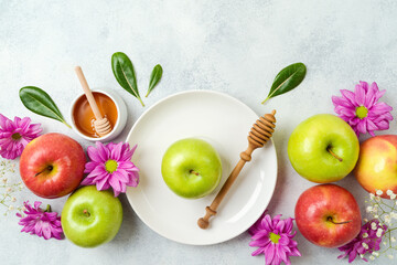 Jewish holiday Rosh Hashana festive table setting with honey, apple and flowers decoration on gray background. Top view, flat lay