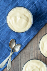 Dessert mit Vanillepudding auf Tisch aus Holz und blauem Tuch