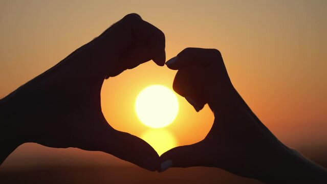Couple shows heart with hands silhouettes at back sunset. Man and woman love each other expressing pure trust and uniting together. Partners enjoy being family closeup